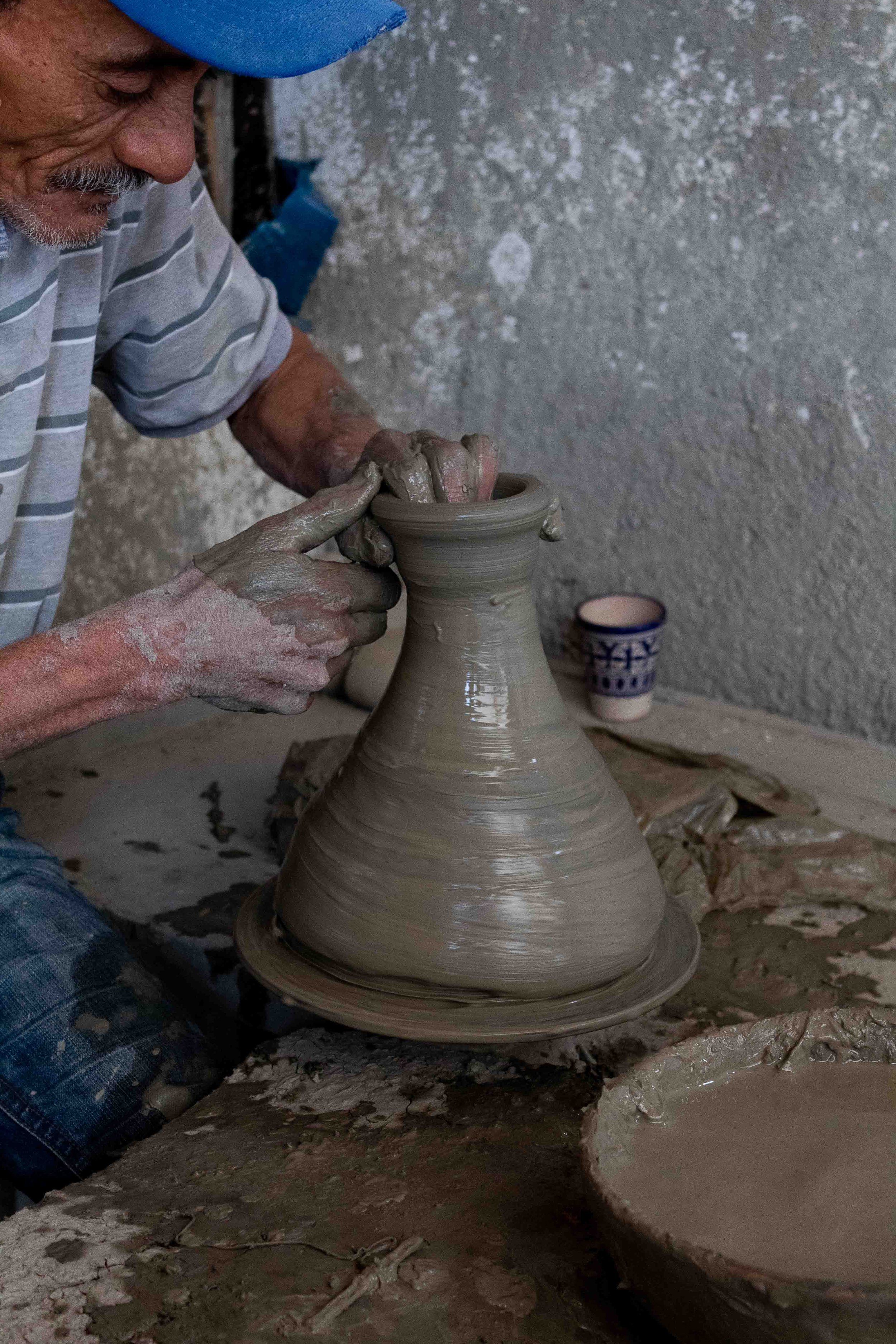 A close up look at a potter and his pottery piece while at a potters wheel